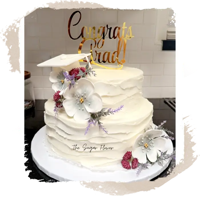 A white cake with flowers and a congrats grad topper.